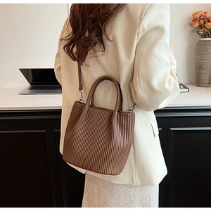 Detailed view of dark brown pleated bucket bag with vertical textures and sleek handles