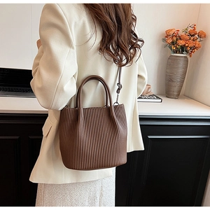 Brown pleated bucket bag detail showing soft matte texture and leather shoulder strap