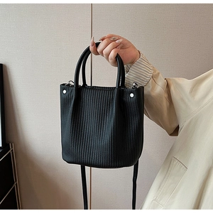 Detailed view of the vertical pleated leather texture on this black bucket tote bag