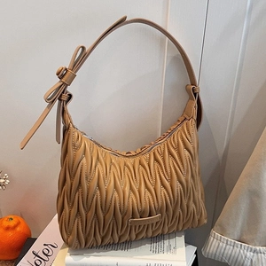 Elegant camel pleated shoulder bag with bow detail and metallic logo plate shown in lifestyle setting
