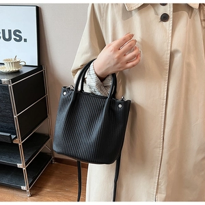 Detail of pleated black bucket bag with vertical texture and silver hardware accents