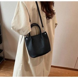 Detail of black pleated bucket bag showing vertical grain texture and silver hardware
