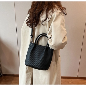 Detail of black pleated bucket bag featuring dual handles and silver metal hardware