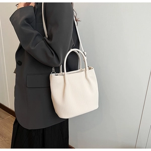 Detail of off-white pleated bucket bag featuring corduroy texture and versatile straps