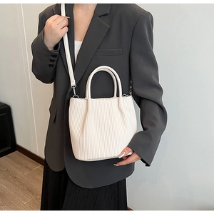 Detail of white pleated bucket bag showing vertical texture and adjustable strap