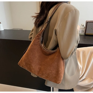 Close-up of brown suede hobo bag with adjustable leather strap and brand logo