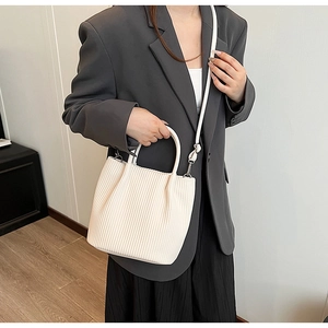 Detail of white pleated bucket bag showing the accordion texture and top handle