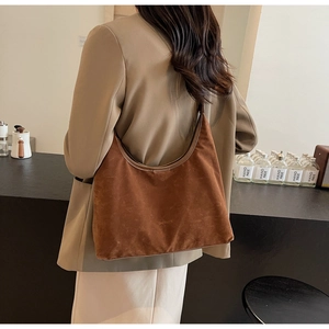 Brown suede hobo shoulder bag with logo detail shown in a casual lifestyle setting