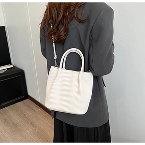 Detailed view of the pleated texture and soft handles on the white bucket bag
