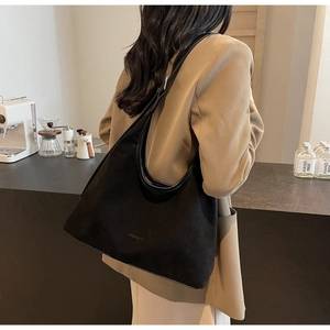 Side view of black suede hobo bag with embossed logo and adjustable shoulder strap