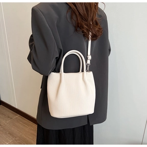 Detailed view of white pleated bucket bag showing vertical texture and crossbody strap