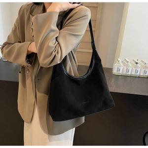 Detail of a vintage black suede hobo shoulder bag shown in a lifestyle indoor setting