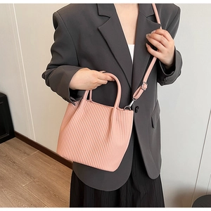 Detailed view of pink pleated bucket bag with round handle and silver metallic hardware