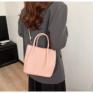 Detailed view of pink pleated bucket bag with metal hooks and adjustable shoulder strap