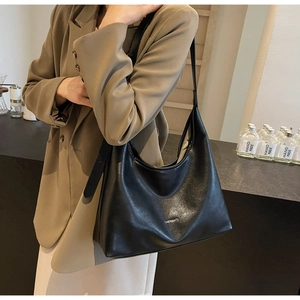 Model wearing a large black leather Hobo shoulder bag with CHERIMATE logo detail