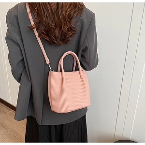 Pink pleated bucket bag worn with a grey blazer for a modern and stylish daily look