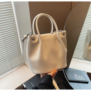 Detail of off-white knit bucket bag with smooth handle and silver metal hardware