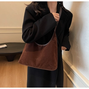 Detailed close-up of brown suede hobo bag with dark leather stitching and logo