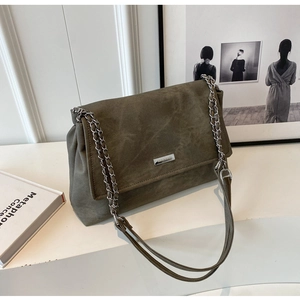 Close-up of olive green tote bag featuring a metal chain strap and brand name plaque