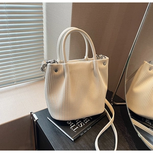 Detail of off-white pleated bucket bag with round handles and silver hardware