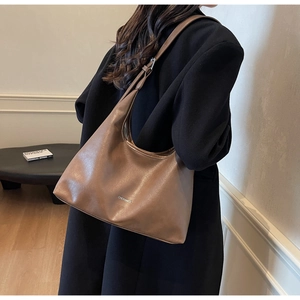 Detail of a brown lychee pattern leather hobo bag worn with a black wool coat