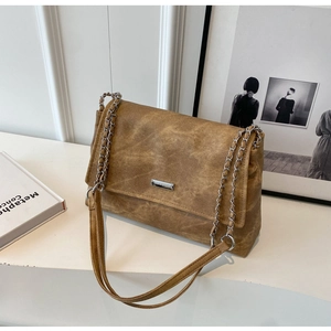 Close-up of vintage brown tote bag with metallic chain strap and silver logo plate