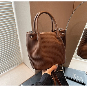 Close-up of pleated dark brown bucket bag featuring silver rivets and a sturdy handle
