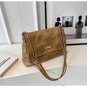 Detailed macro view of vintage brown suede tote with metal chain strap and logo