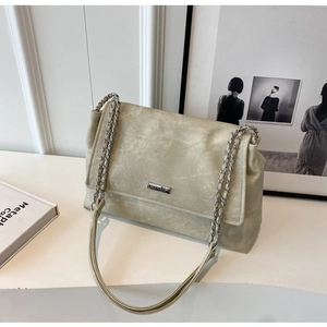 Detail of sage green suede tote bag with silver chain strap and metal logo plaque