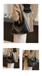 Detailed macro view of soft black leather texture and white logo on large hobo tote bag