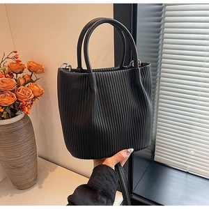 Detail shot of black pleated leather bucket bag with cylindrical handle and strap