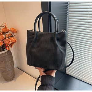 Close-up of black pleated bucket bag showing vertical texture and leather handles