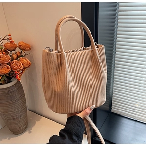 Detail of pleated beige bucket bag with round handle and vertical textured fabric