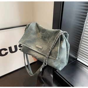 Detail of blue washed denim texture and silver chain strap on vintage shoulder bag
