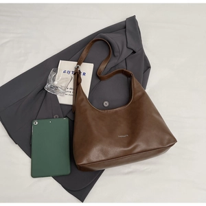 Top view of deep brown leather tote bag with CHERIMATE logo on white fabric background