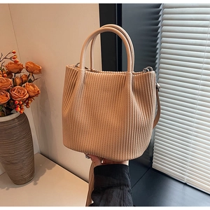 Detail of apricot corduroy bucket bag with pleated texture and soft fabric handle