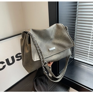 Close-up of grey leather handbag with silver chain strap and metal brand plate detail
