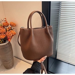 Detail of brown pleated bucket bag with sturdy round handles and textured finish