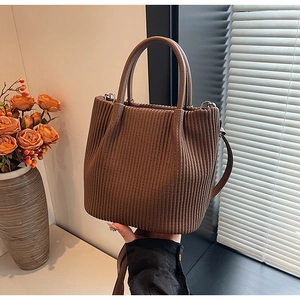 Close-up of a dark brown pleated bucket bag with dual handles and a long shoulder strap