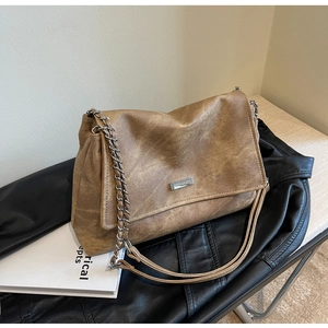 Close-up of vintage brown PU leather bag with silver chain strap and metal logo plate