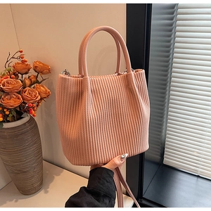 Close-up of soft pink pleated bucket bag showing vertical textures and top handle