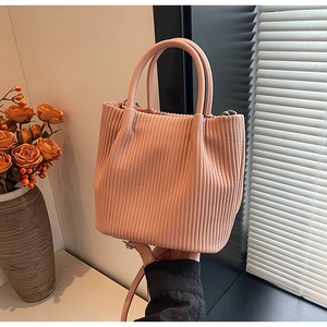 Detailed view of pink corduroy pleated bucket bag with dual handles and crossbody strap