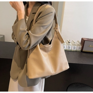 Close-up of beige lychee grain tote bag with wide shoulder strap and side tassel detail