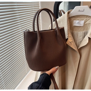 Detailed view of dark brown pleated leather bucket bag with a sturdy rounded top handle