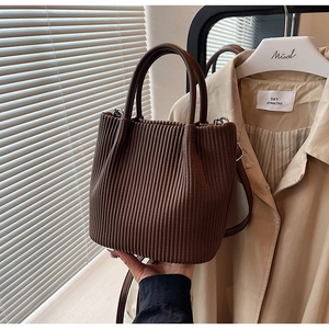 Detail of coffee brown pleated bucket bag with metallic silver D-ring and smooth handle