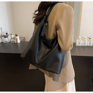 Detail of premium black lychee-grain leather tote with side decorative tag