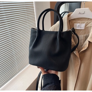 Detail of black pleated bucket bag with dual handles and detachable shoulder strap