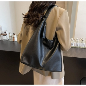Detail of black pebbled leather tote bag with wide shoulder strap on model's back
