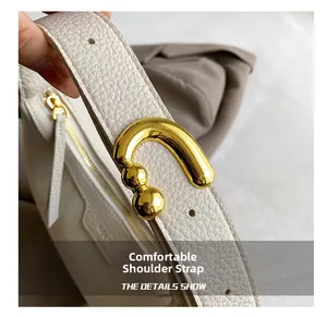 Detail of white lychee leather handbag showing golden U-shaped buckle and sturdy shoulder strap