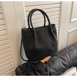 Detailed view of black pleated bucket bag featuring cylindrical handles and slim strap